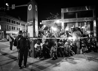 Image of reporters standing behind a police line with an officer in front
