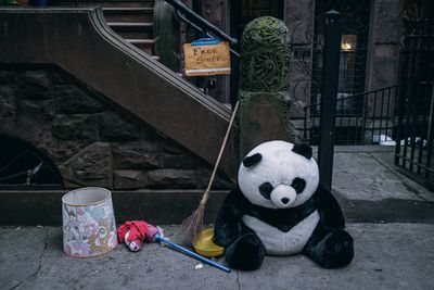A stuffed animal of a panda and several abandoned objects on a sidewalk